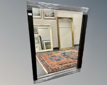 A contemporary mirror in a black frame, 86cm by 111cm.