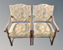 A pair of 20th century oak scroll arm armchairs upholstered in a floral fabric.