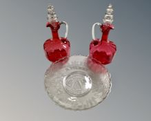 A pair of cranberry glass decanters with stoppers together with a Davidson's glass Christmas plate.