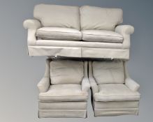 A three piece lounge suite upholstered in a beige fabric.