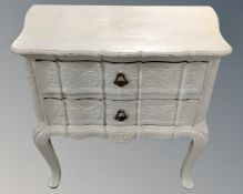 A painted French style two drawer bedside table on raised legs.