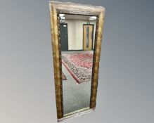 A contemporary mirror in a golden frame, 64cm by 158cm.