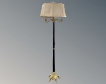 A decorative metal and brass three way standard lamp with shade.