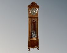 A Continental beech longcase clock with brass embossed dial, pendulum and weights.