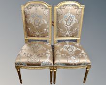 A pair of gilt dining chairs upholstered in a classical fabric.