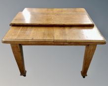An Edwardian oak wind out dining table with leaf.
