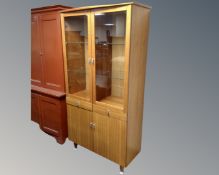 A contemporary double door glazed bookcase fitted with cupboards and drawers beneath,