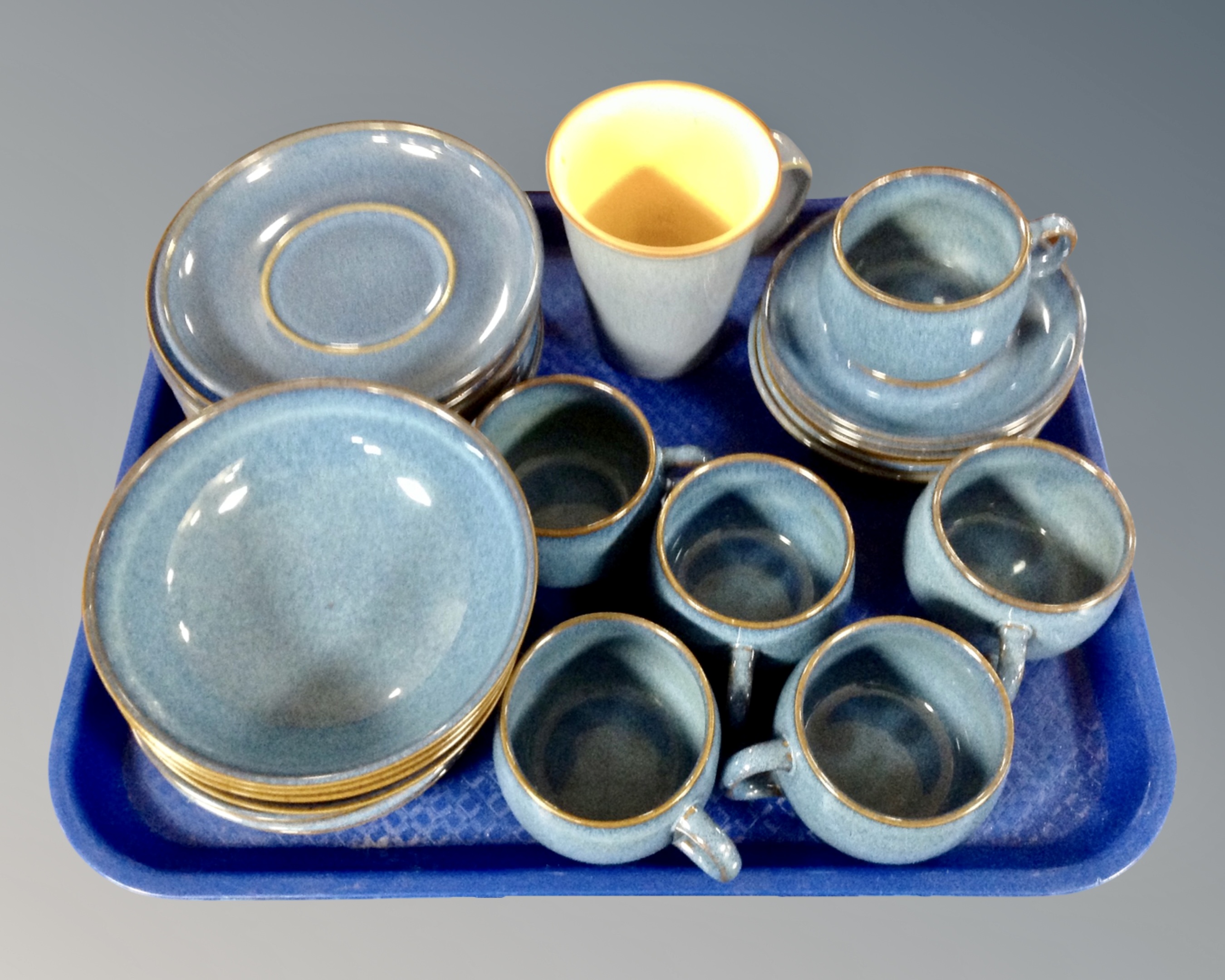 A tray of approximately 27 pieces of Denby blue glazed teacups and dinnerware.