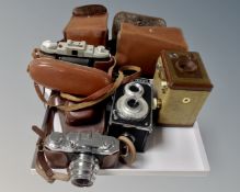 A box containing four vintage cameras in cases including Halina, Kodak Brownie etc.