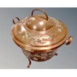 An antique copper lidded twin handled pot on raised legs.