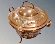 An antique copper lidded twin handled pot on raised legs.