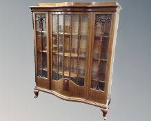 A late 19th century mahogany bow fronted glazed display cabinet on raised legs.