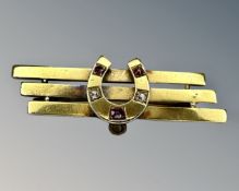 A 15ct gold ruby and diamond horseshoe brooch, width 3.7cm, 2.3g.