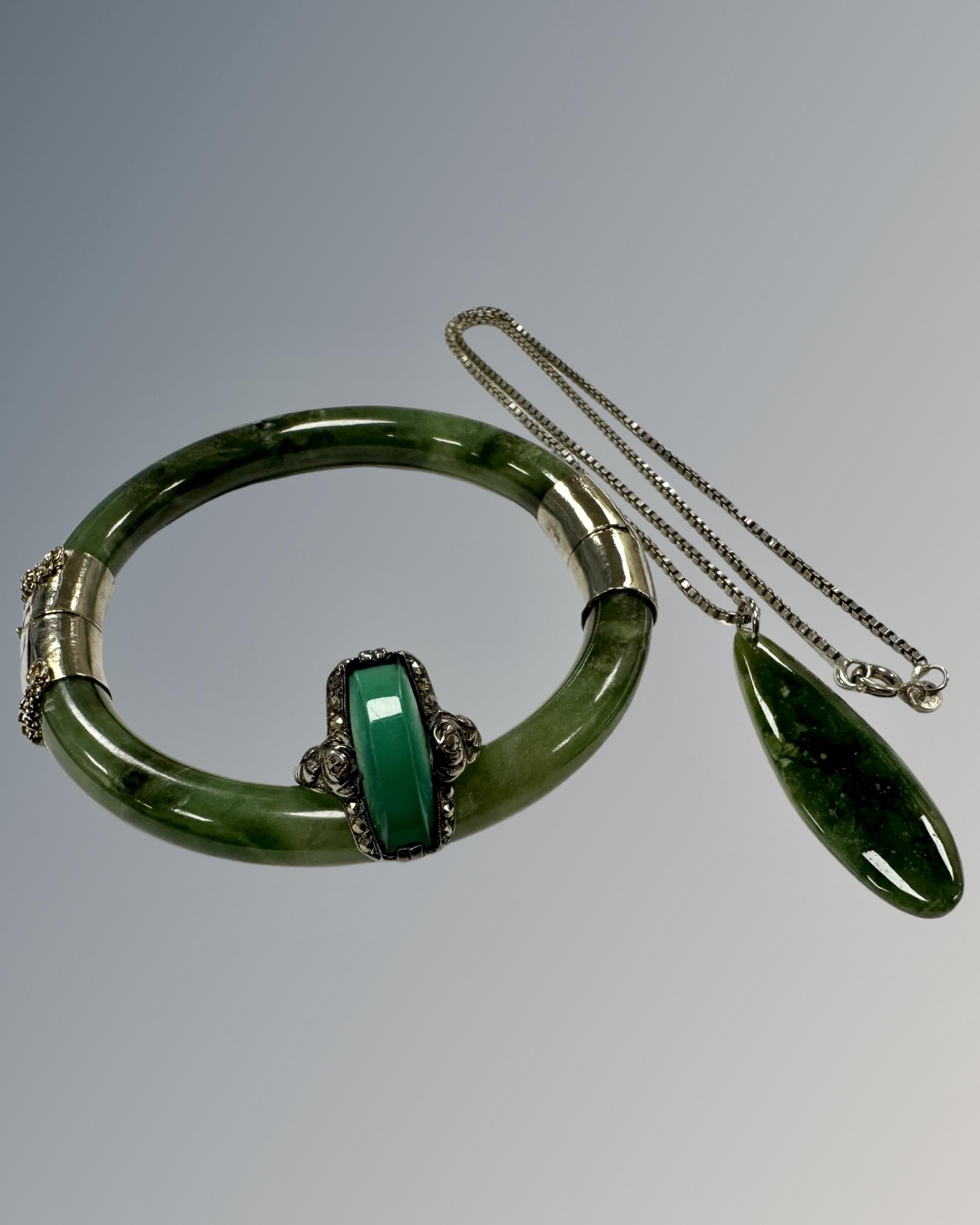 A moss green jade bangle mounted in white metal, internal diameter 60 mm,