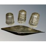 Three silver thimbles and a silver spool.