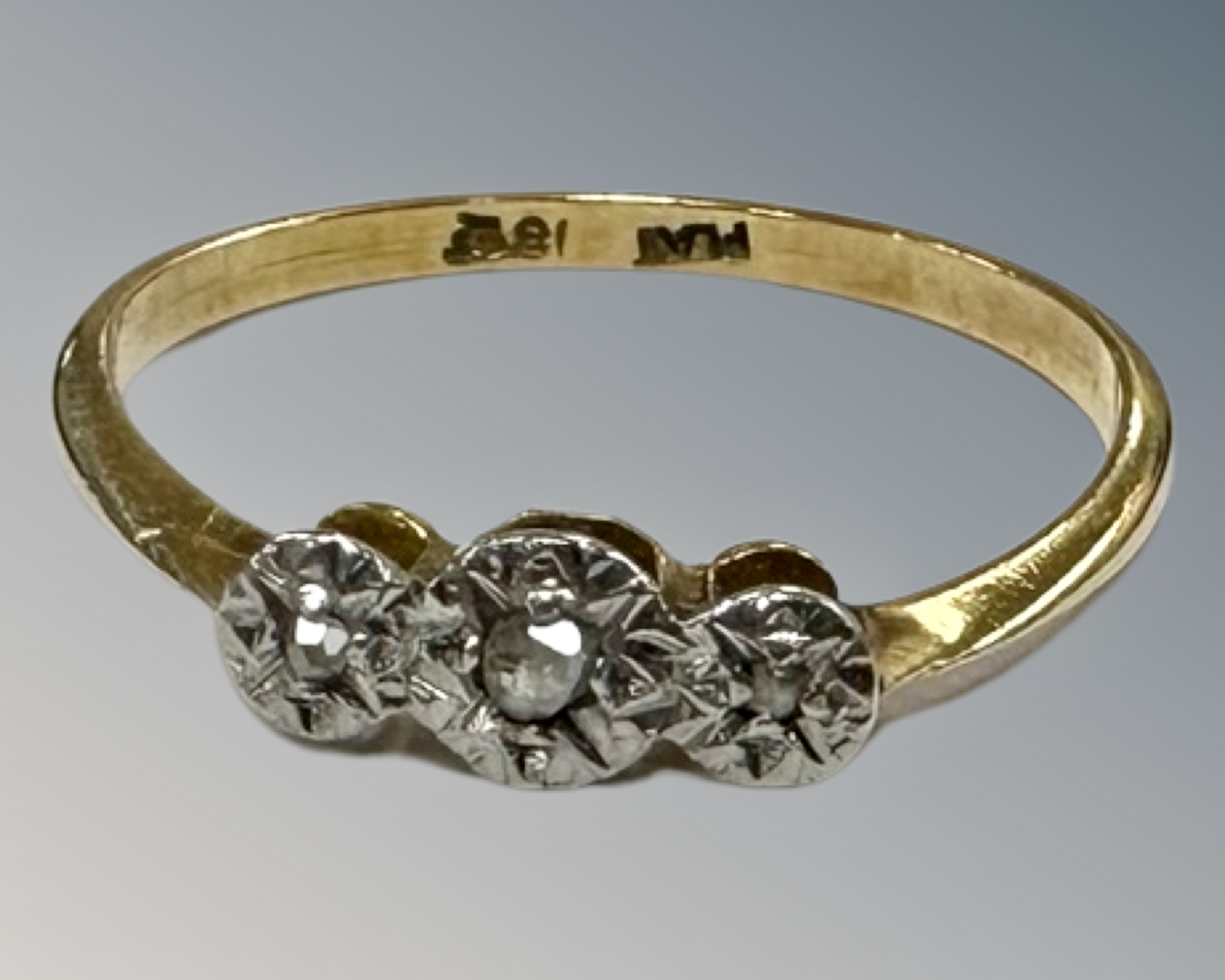 An 18ct yellow gold platinum set three stone diamond ring, size P, 1.7g.
