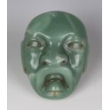 A pre-Columbian Olmec style carved green jade mask, probably 900-450 BC, with pierced holes to