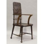 An Edwardian Arts and Crafts mahogany armchair by James Shoolbred & Co, the carved foliate top above