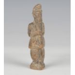 An ancient terracotta figure, probably Sumerian, modelled with his hands clasping his long beard,