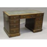 An Edwardian oak twin pedestal desk, the top inset with tooled leather above an arrangement of
