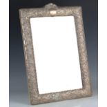 An Edwardian silver mounted rectangular dressing table mirror, pierced and embossed with flowers,