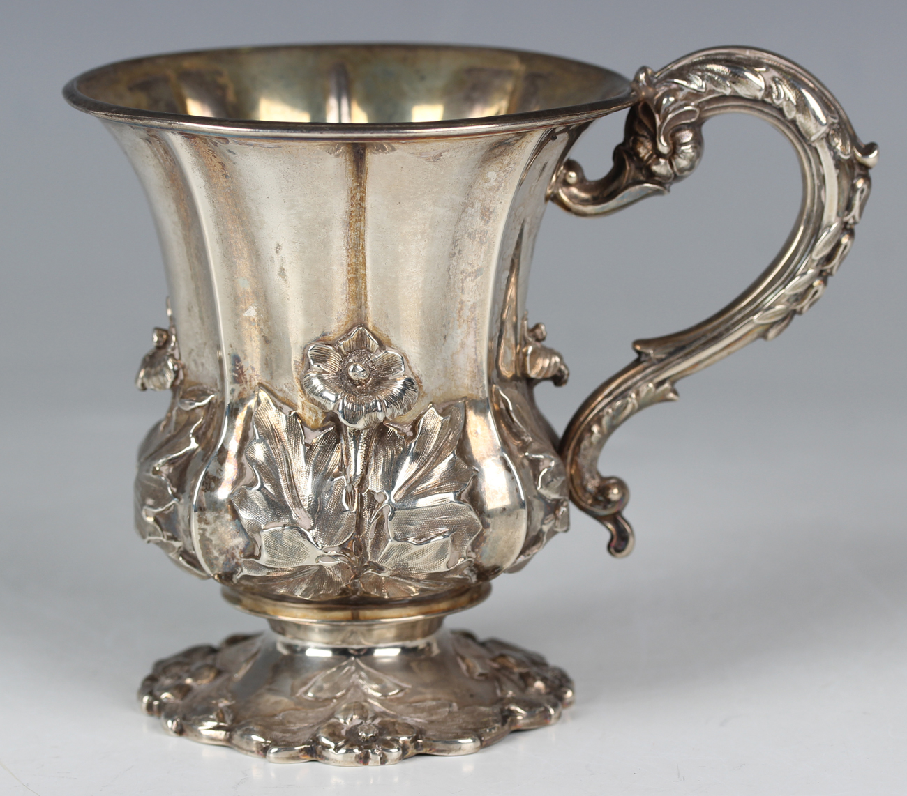 A William IV silver christening mug of lobed tapering form, decorated in relief with a band of