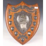 An early 20th century oak and plate-mounted shooting prize shield trophy, the central cartouche