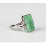 A white gold and jade ring, mounted with a rectangular jade with carved and pierced decoration