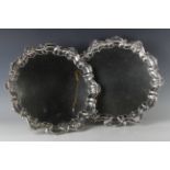 A pair of George V silver circular salvers, each with raised 'C' scroll and scallop shell rims, on
