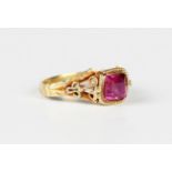 A gold and red gem set solitaire ring, possibly Asian, mounted with a square cut red gem between