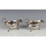 A pair of Edwardian silver sauce boats, each with wavy rim and foliate capped flying scroll