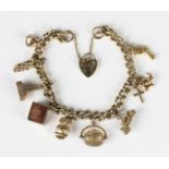 A 9ct gold curblink charm bracelet on a 9ct gold heart shaped padlock clasp, fitted with three 9ct