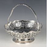 A George V silver circular swing handled basket, the wavy rim above pierced scroll sides, raised