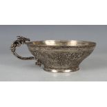A Persian silver cup, the shallow circular body engraved with figures, the foliate scroll handle
