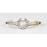 A late Victorian gold, silver set and diamond bangle with a horseshoe shaped motif, mounted with a