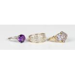 A platinum ring, claw set with a circular cut amethyst between diamond three stone shoulders,