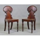 A pair of late Regency mahogany hall chairs, the shaped backs above solid seats, on ring turned