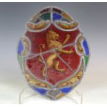 A 19th century stained and leaded glass shaped oval panel, decorated with a lion rampant within an