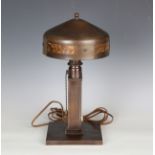An early 20th century Arts and Crafts copper table lamp by Roycroft, the domed shade inset with four