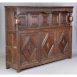 A large 17th century oak court cupboard with parquetry inlaid borders, the frieze with carved