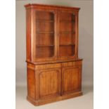 A mid-Victorian mahogany bookcase cabinet, the glazed top enclosing three adjustable shelves above