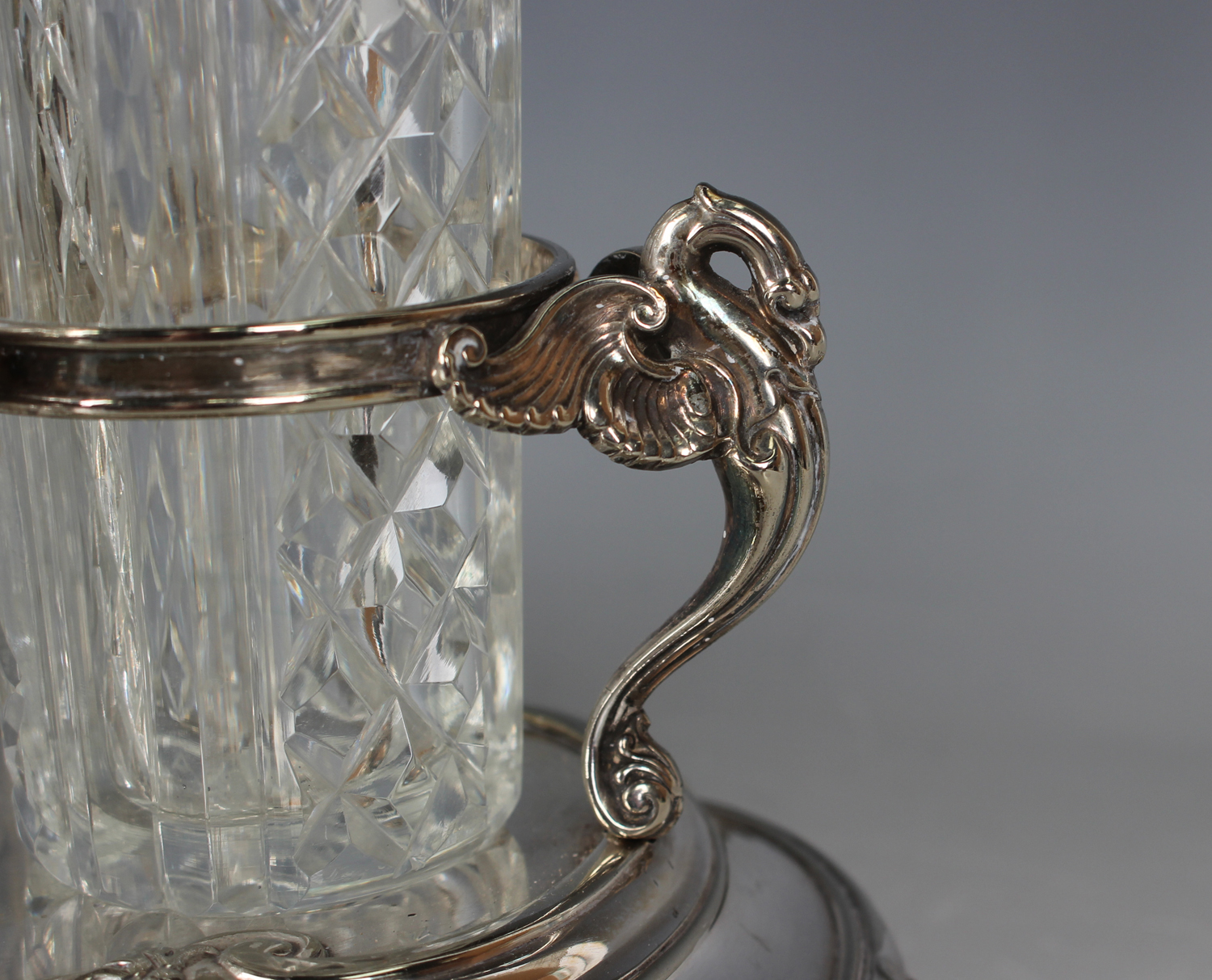 A late Victorian plated eight-bottle cruet stand with central scroll handle above swan supports, - Image 3 of 3