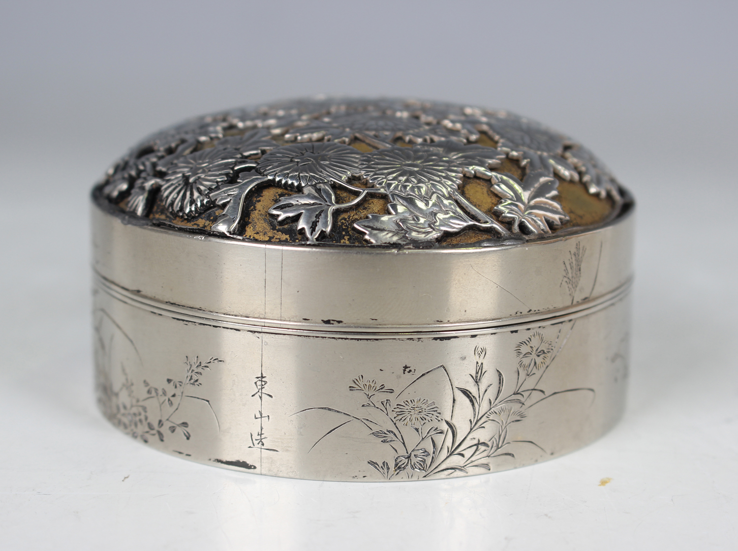 A Japanese silver circular box and cover, the domed cover cast and pierced with chrysanthemums