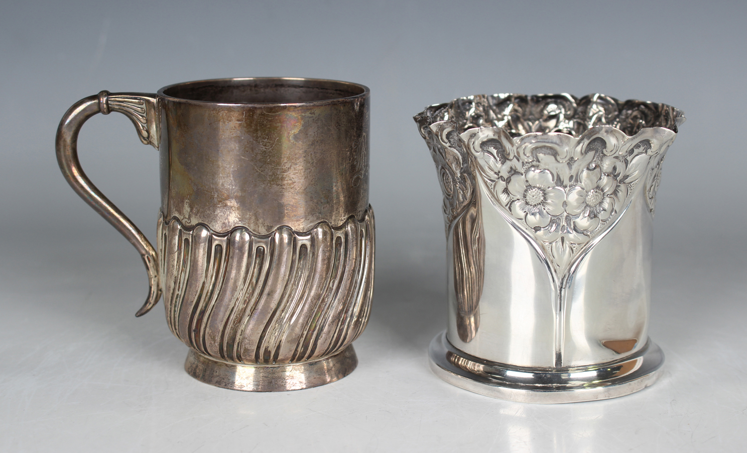 An Edwardian silver vase of slightly flared cylindrical form, embossed with panels of flowers, on