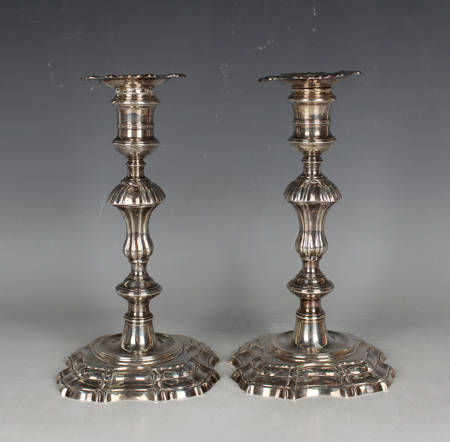 A pair of George II cast silver candlesticks, each with a detachable nozzle and turned urn shaped