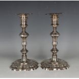 A pair of George II cast silver candlesticks, each with a detachable nozzle and turned urn shaped