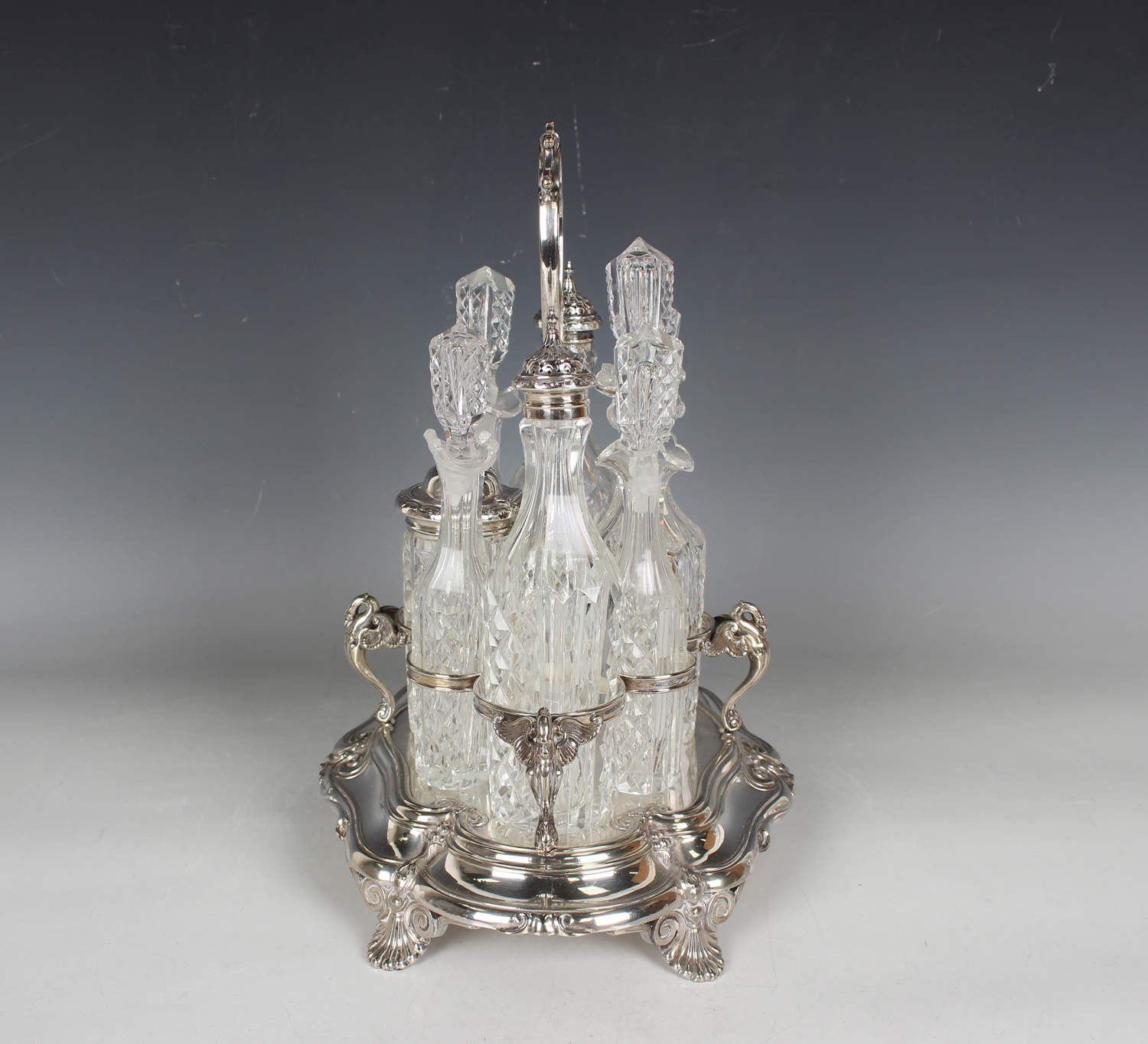 A late Victorian plated eight-bottle cruet stand with central scroll handle above swan supports, - Image 2 of 3