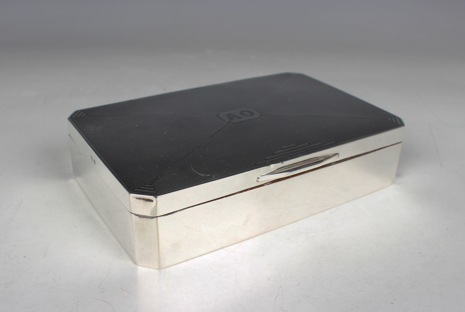 A George V silver canted corner rectangular cigarette box, the engine turned hinged lid with