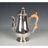 A George V silver baluster coffee pot with domed hinged lid, scroll spout and handle, on a