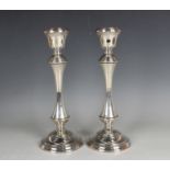 A pair of Elizabeth II silver candlesticks with reeded urn shaped sconces above tapering stems and